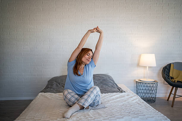 istock Woman waking up stretching in bed at home 2241046987