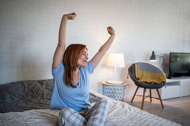 istock Woman waking up stretching in bright bedroom 2241047087