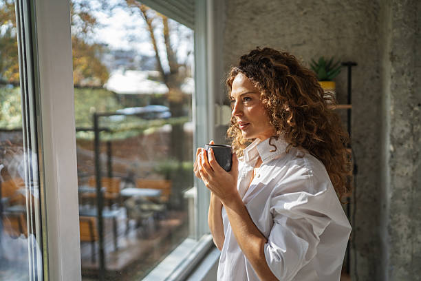 istock woman enjoying coffee looking out window 2241047528