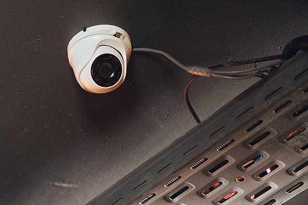 istock White dome security camera mounted on a dark ceiling with wiring and a metal cable tray. Surveillance technology for safety and monitoring. 2241048981