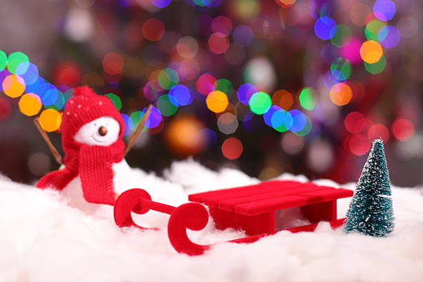 Red holiday sled on snow and Christmas lights background, holidays concept