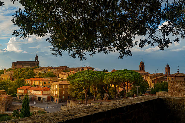 istock Tuscan town with churches and pine trees, viewed under large tree, historic hilltop, warm sunlight 2241055625