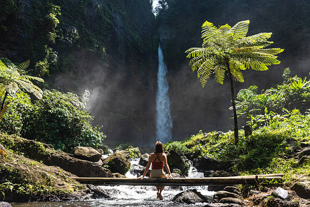 istock Woman sitting on a bamboo bridge over a river in a tropical rainforest 2241055935
