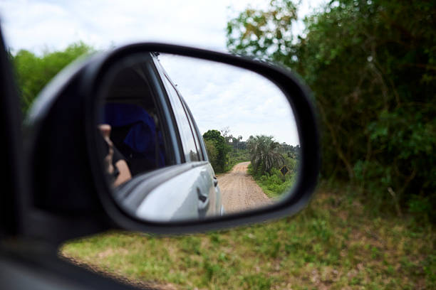 istock Car rearview mirror reflecting a travel scene, a dirt road. 2241063489