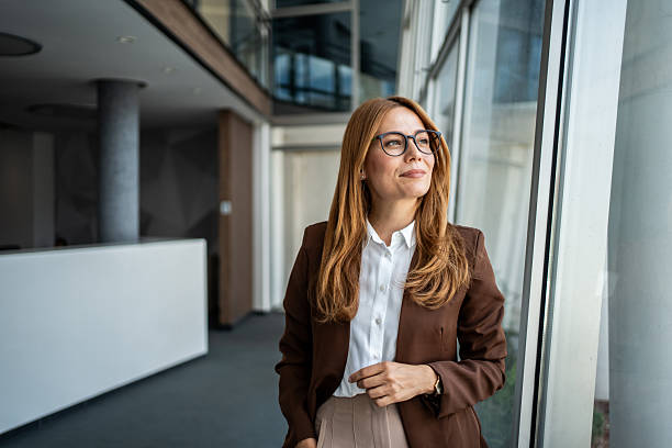 istock Businesswoman looking out office window with ambition 2241063608