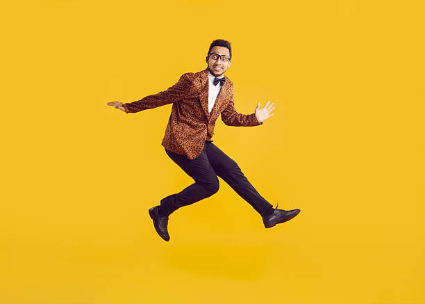 istock Cheerful funny dark-skinned young man in leopard jacket having fun jumping on yellow background. 2241065648