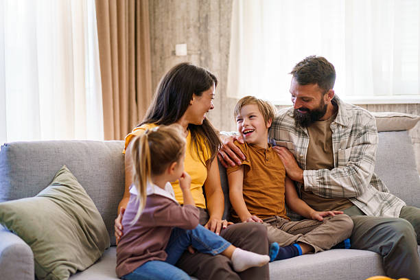 istock Happy family with children sitting and laughing on a sofa 2241069042
