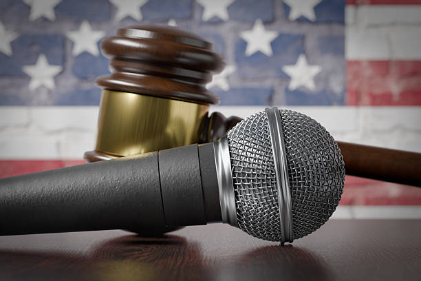 Microphone in sharp focus with a nervous sweaty public speaker or politician blurred in the background preparing to make a speech as he wipes sweat off of his brow