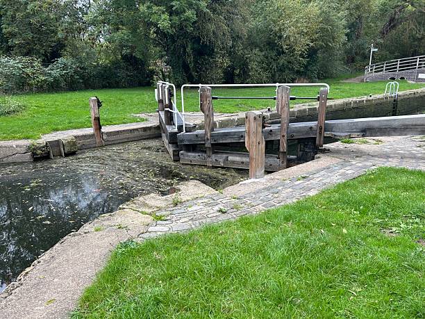 istock Wooden Canal Lock Gate With Bridge In Park Setting And Lush Green Grass 2241078338