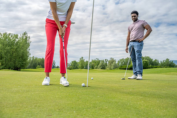 istock Golfer in White and Red Preparing to Putt on Lush Course 2241090070