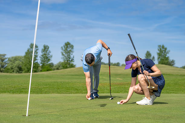 istock Two Golfers on Course, One Preparing to Putt near Yellow Flag 2241090082