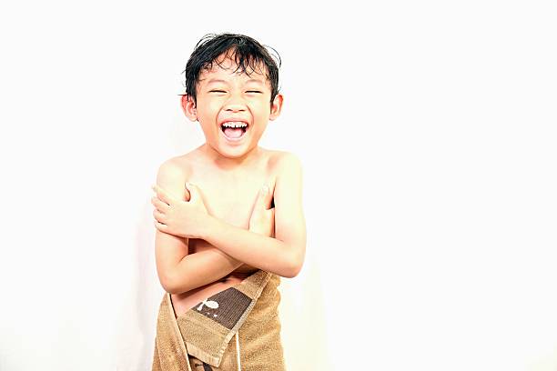 Cheerful little boy laughing while wrapped in towel after bath, showing joy and freshness of clean routine.