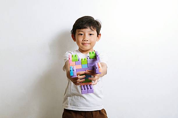Excited young boy proudly showing colorful plastic building block creation, concept of imagination, fun learning, and creativity for kids.