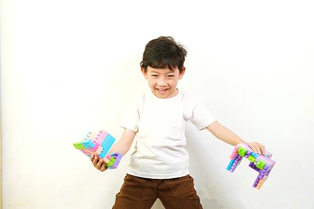 Cute little boy playing with colorful plastic building block bricks, expressing joy and creativity during fun learning at home.