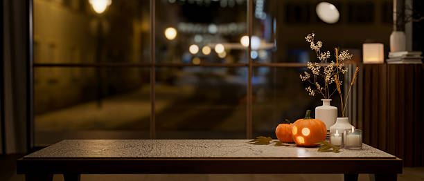 Glowing jack-o-lantern halloween pumpkin aside candle on marble table and glass wall with night view