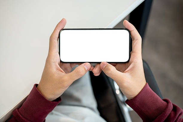 istock A man holding white screen smartphone horizontally as sitting indoors at table in a cafe or library. 2241105768