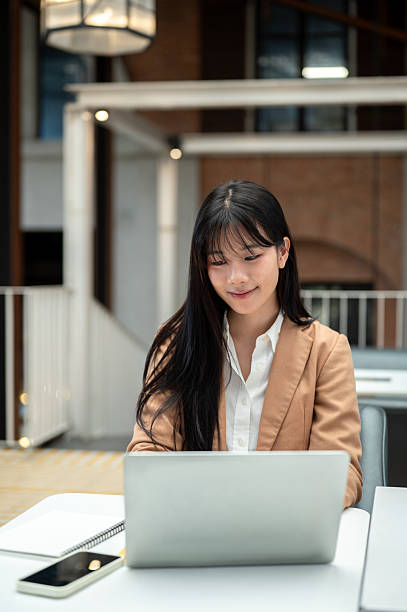 istock Asian businesswoman or office worker looking using laptop aside phone and notebook on table in cafe. 2241106105