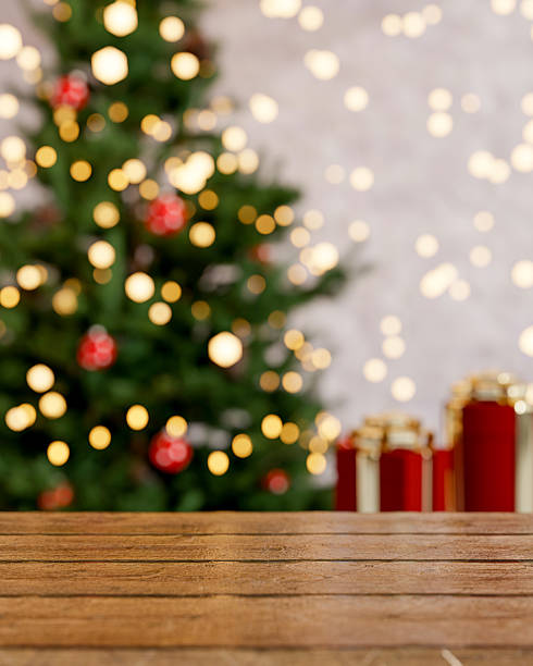 istock Empty wooden counter table across Christmas trees with blurred present gift box and string lights. 2241108811