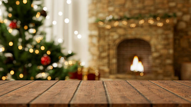 istock Empty wooden counter table aside Christmas tree and blurred lighting golden fireplace in living room 2241108817