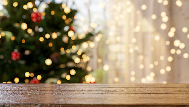 istock Empty wooden table across the Christmas trees and string lights decors curtain in bright living room 2241108838