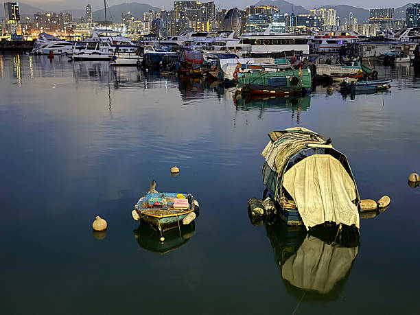 istock Twilight Harbor Contrast: Traditional Boats and Modern Skyline Reflected in Evening Waters 2241108928