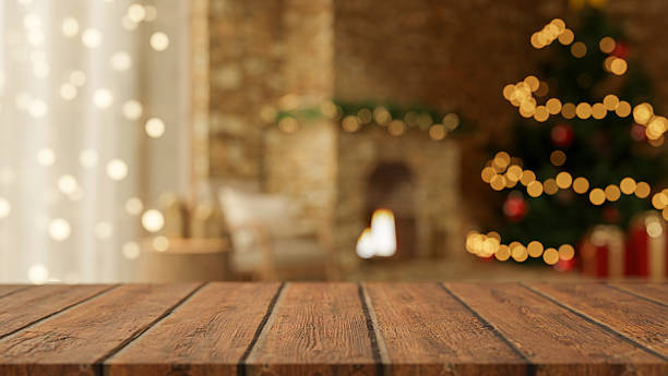 istock Empty wooden counter table across blurred Christmas tree and lighting fireplace in cosy living room. 2241110628
