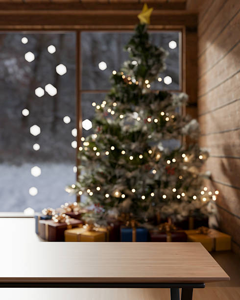 istock Empty wooden table across present gift box under Christmas trees with string lights in cosy living room. 2241111911