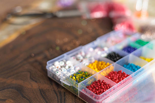 istock Colorful plastic beads organized in transparent container for crafting on wooden table 2241118374