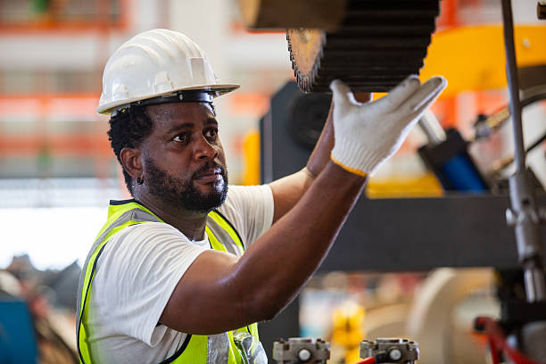 Engineer male African American white helmet working setup gear drive machine engine in factory Industry. maintain machinery and ensure efficient operation.
