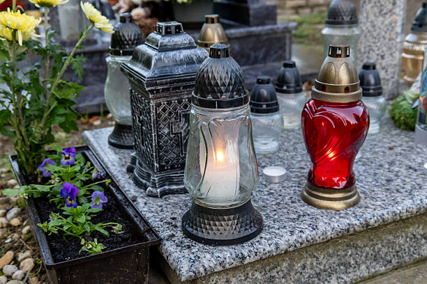 istock Gravestone with lit candles and purple pansies 2241120350