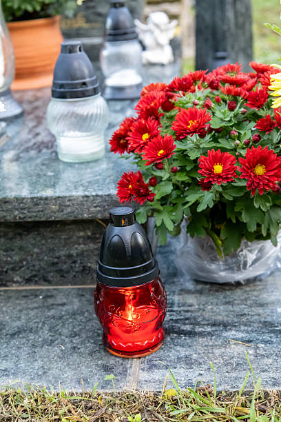 istock Red memorial candle with chrysanthemum flowers on gravestone 2241120586