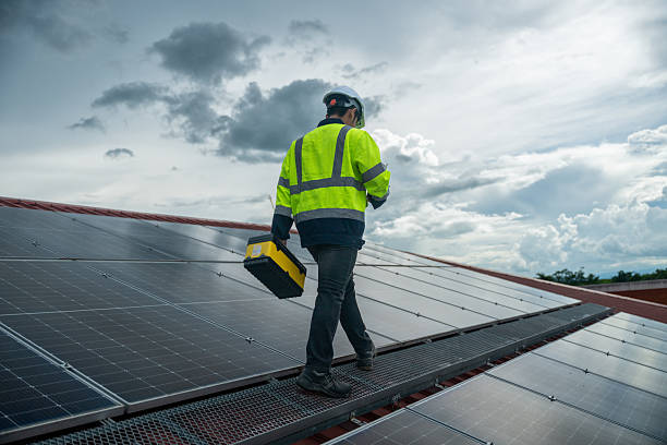 istock Engineer wearing helmet and reflective jacket on rooftop with solar panels inspecting and maintaining solar power system holds toolbox and tablet green power and environment eco-friendly electricity generation sustainable future concept. 2241121260