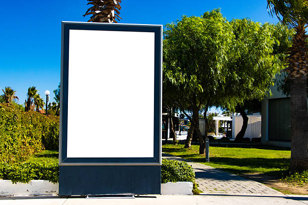 istock Outdoor billboard mock-up in landscaped urban park, featuring editable white display surface framed in dark material, ideal for commercial use, advertising, or seasonal campaigns. 2241121937