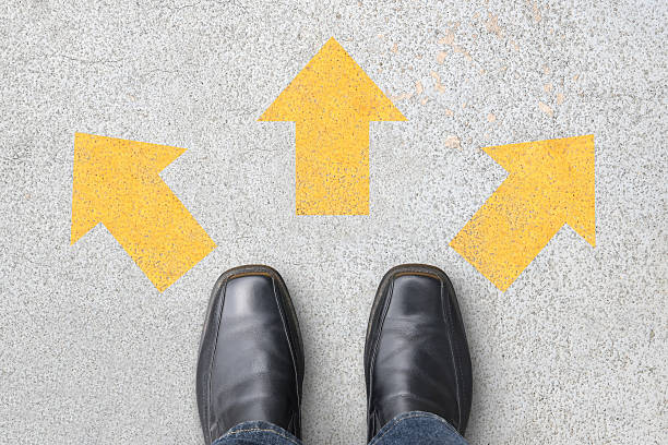 istock businessman standing at crossroads with three direction arrows on floor 2241123234