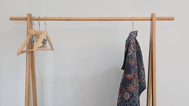 istock Minimal wooden clothes rack with hangers and patterned shirt 2241123867