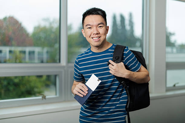 istock Smiling international student holding passport and backpack 2241127166