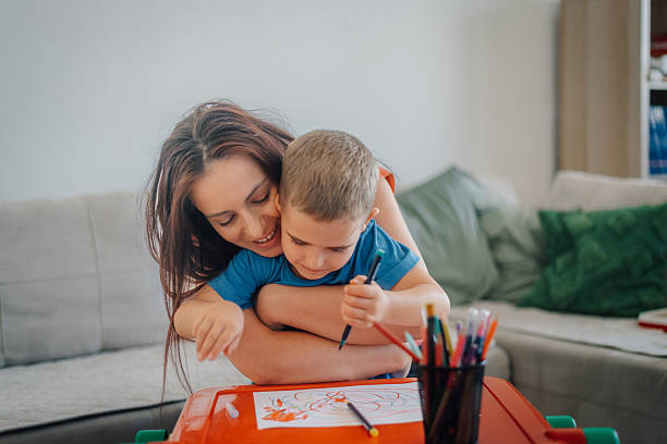 istock Mother hugging son while drawing with colored pencils at home 2241131963