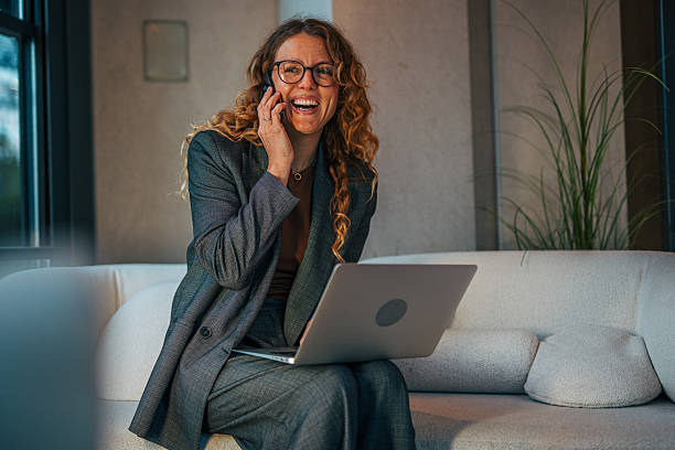 istock Woman smiling and talking on phone using laptop 2241132568