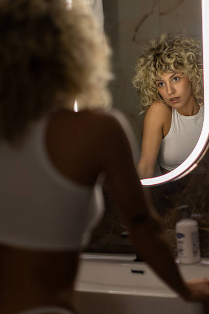 istock Young woman looking at herself in the mirror 2241135336