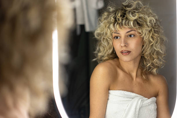 Young beautiful blond woman looking at herself in the mirror.