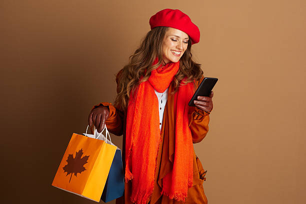 Autumn Shopper Checking Phone with Bags stock photo