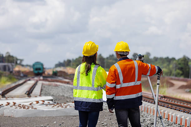 istock Two railway engineers wearing safety helmets and reflective jackets inspect new rail track construction with surveying equipment. The image shows teamwork, planning, and infrastructure development progress. 2241144169