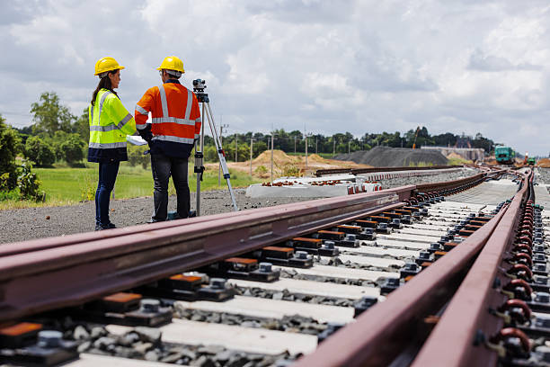 istock Two engineers in safety gear stand beside newly constructed railway tracks using surveying equipment. The image highlights teamwork, infrastructure development, precision, and modern rail construction. 2241144194