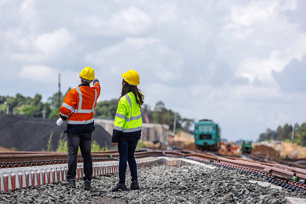 istock Two railway engineers wearing helmets and reflective jackets inspect new rail tracks under construction. One points toward the project site, symbolizing teamwork, direction, and infrastructure progress. 2241144211