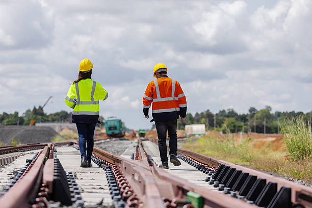 istock Two railway engineers wearing helmets and reflective jackets inspect new rail tracks under construction. One points toward the project site, symbolizing teamwork, direction, and infrastructure progress. 2241144506