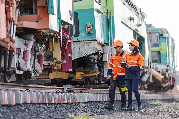 istock Two rail engineers wearing safety helmets and reflective uniforms inspect a railway track and train maintenance system, discussing technical details for transportation safety and engineering efficiency. 2241145215