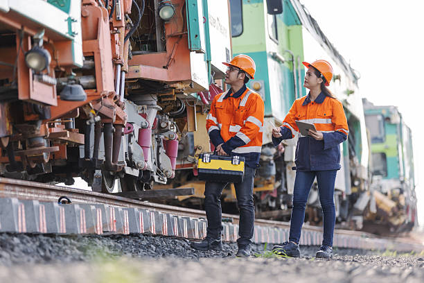istock Two rail engineers wearing safety helmets and reflective uniforms inspect a railway track and train maintenance system, discussing technical details for transportation safety and engineering efficiency. 2241145231