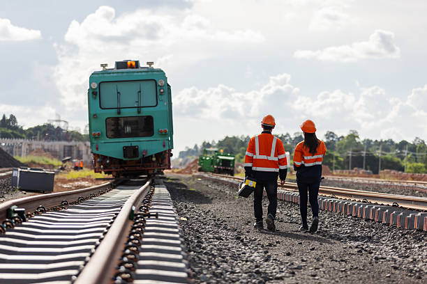 istock Two rail engineers in safety gear walk along a newly constructed railway track toward a maintenance train, representing innovation, teamwork, and development in modern transportation infrastructure. 2241145254