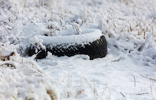 A tire is covered in snow. It is in the snow. The tire is black