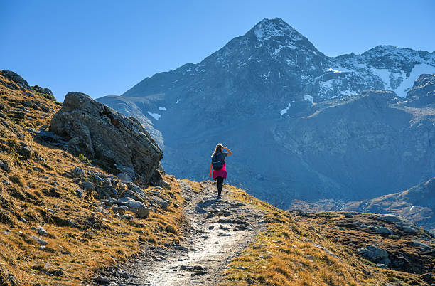 istock Young woman with backpack hiking along rocky mountain trail 2241146231